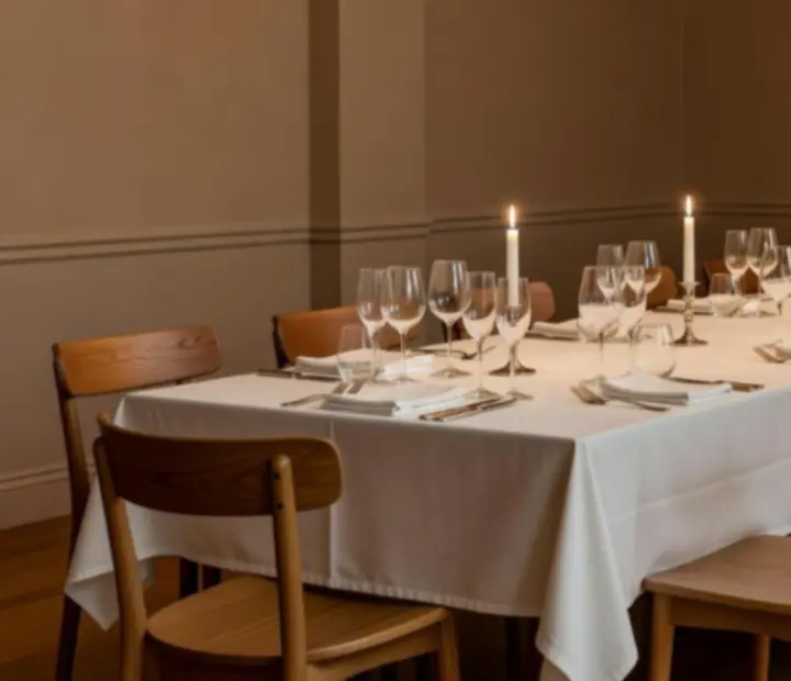 Table privatisée dressée avec nappes blanches et verres alignés pour un dîner exclusif.